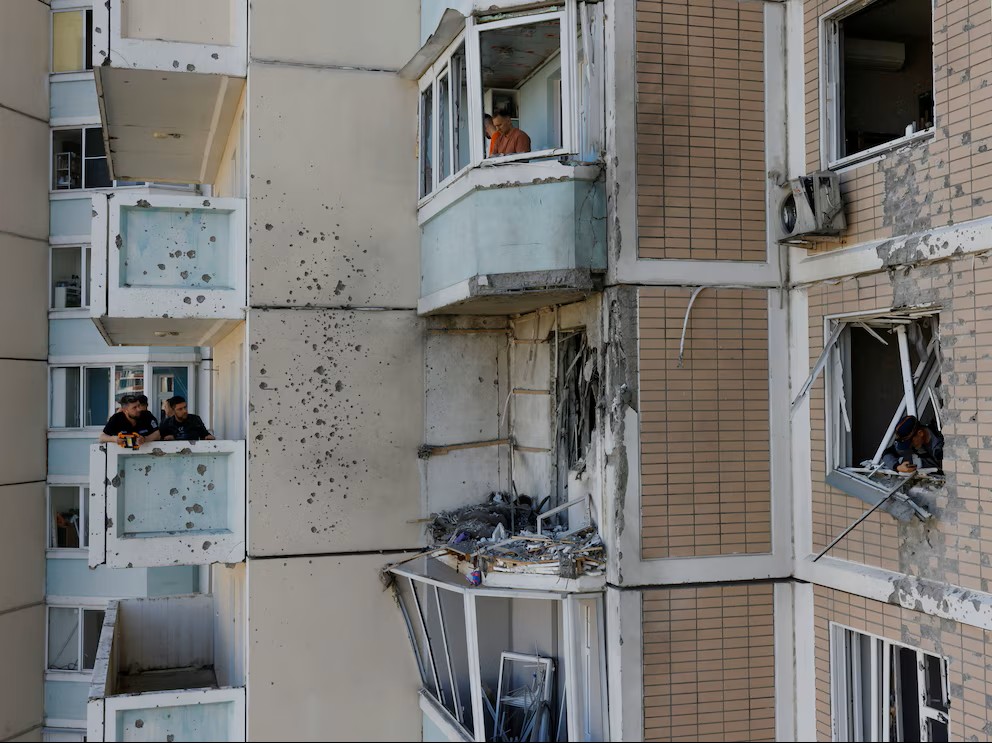 Los vecinos retiran los escombros de las ventanas rotas de un edificio de apartamentos dañado tras un ataque con drones ucranianos en el marco del conflicto entre Rusia y Ucrania en Krasnogorsk, en la región de Moscú (REUTERS/Stringer)