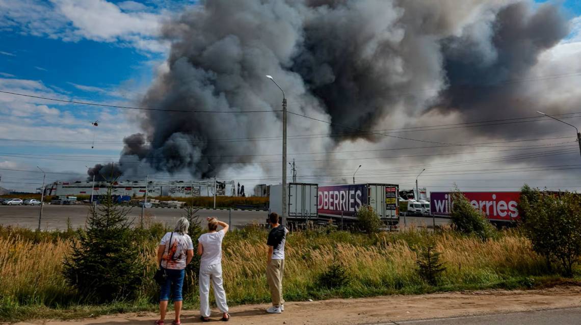 Personas observan cómo se eleva humo sobre una instalación de Wildberries tras un presunto ataque con drones ucranianos en el Parque Industrial Koledino, cerca de Podolsk, en la región de Moscú, Rusia. (Foto: EFE).